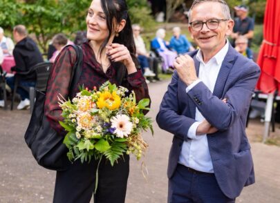 Moderator und Frau mit Blumenstrauß im Bild