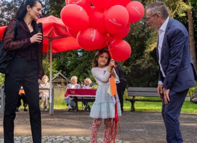 Mädchen mit vielen roten ProSeniore Luftballons